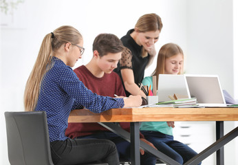 Canvas Print - Group of teenagers doing homework with teacher in classroom