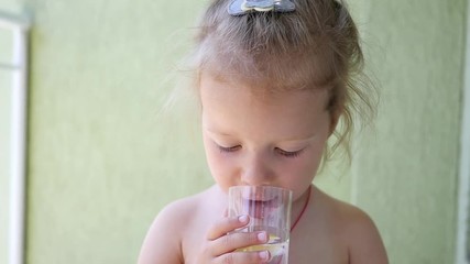 cute child girl drinking a cup water with piece of lemon - healthy body care consumption