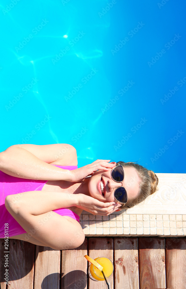 Beautiful young woman resting near swimming pool
