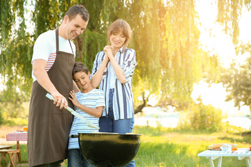 Canvas Print - Family cooking tasty food on barbecue grill outdoors