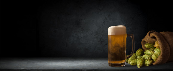 Beer in mug on wooden table near brick wall