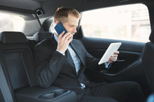 Executive Businessman At The Back Of Car Using A Mobile Phone