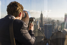 USA, New York City, Man Looking Through Coin-operated Binoculars On Rockefeller Center Observation Deck