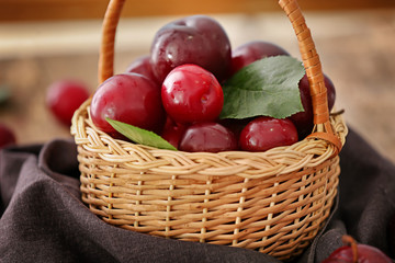 Sticker - Wicker basket with ripe juicy plums on table