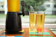 Dispenser and glasses with cold beer on table
