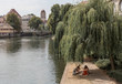 © Simplementbeau. - Vue sur une rivière et un groupe d'amis faisant un pique-nique en ville