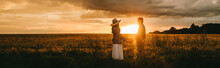 Stylish Couple Holding Hands On Meadow At Beautiful Sunset With Back Light, Love Story