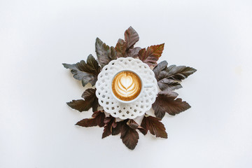 Wall Mural - A cup of fragrant coffee cappuccino. Nearby lie autumn leaves. Simple minimalistic autumn design.