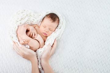 sleeping newborn baby in mother hands - hearth shape