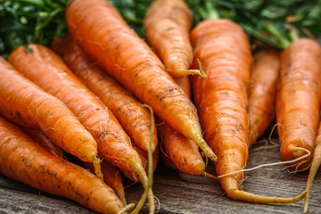 Close-up of bundle of carrots on a rustic wooden table. Concept for fresh vegetarian, organic raw food and harvest.