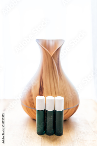 Fotografie, Obraz Wooden bamboo essential oil diffuser closeup, with three glass bottles, steam mo
