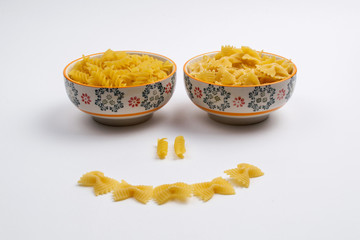 Two ceramic bowls full of pasta make up a smiling face