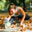 © Microgen - Woman stretching in the park, in the fall.