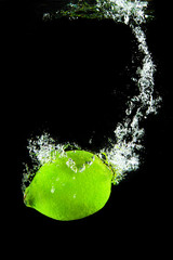 Fresh sour green lime splashing into water with vibrant color contrast