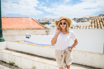 Wall Mural - Young pretty hipster cheerful girl posing on the street at sunny day, having fun alone, stylish vintage clothes hat and sunglasses. travel concept.