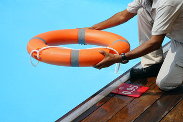 Wall Mural - Hotel worker throws a lifeline to a drowning pool. Salvation of a sinking person. Life ring in swimming pool. Red lifebuoy pool ring.