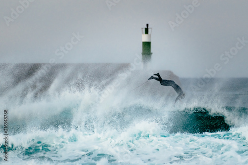 Fotografia, Obraz Surfer jumping over a wave during a windy day