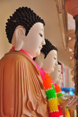 Buddha statue in a row in Buddhist temple with flowers ring hanging on neck