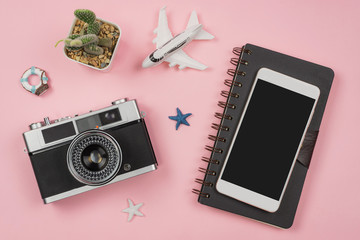 Wall Mural - Retro camera with toy plane on pastel pink background with travel diary