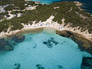 Wall Mural - View from above, aerial view of an emerald and transparent Mediterranean sea with a white beach full of colored beach umbrellas and tourists who relax and swim. Costa Smeralda, Sardinia, Italy.