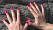 Le mani conle unghie rosse su una roccia