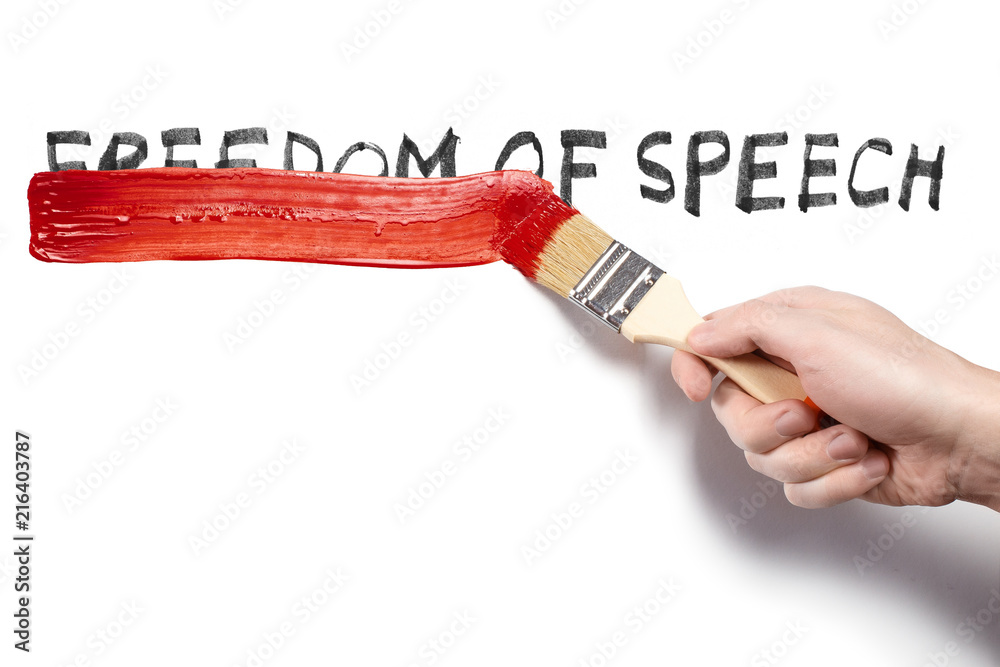 Hand painting over the words "Freedom of speech" using a red brush, isolated on white background
