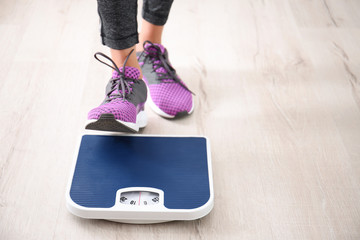 Woman measuring her weight using scales on floor