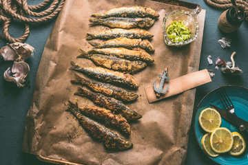 Grilled sardines on baking tray with ingredients: lemon, garlic and herbs for tasty seafood eating. Cooking preparation of fishes