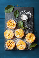 Wall Mural - Autumn mini apple pies on black slate board top view. Tasty pastry desserts.