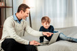 © zinkevych - Look here. Nice positive man pointing at the laptops screen while showing a picture to his son