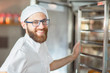 © salomonus_ - Portrait of a young beautiful baker with fresh bread and an oven in the background