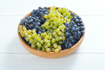 Canvas Print - white and red grapes on wooden bowl, white wood table background