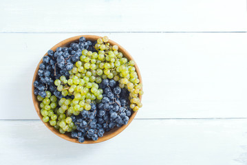 Canvas Print - white and red grapes on wooden bowl, white wood table background