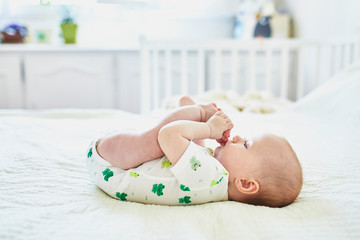 Wall Mural - Baby girl putting her feet into mouth and suckling toes