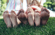 © Yakobchuk Olena - Focus on female feet lying on grass in park. Mother and kids are admiring summer days side by side