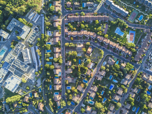 An aerial view from the drone of a neighborhood with its swimming pools inside a forest in the outskirts of Madrid city seeing the urban planning of the area with its home and streets aligned