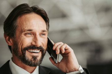 Portrait of laughing male worker with attractive smile telling on mobile. Copy space