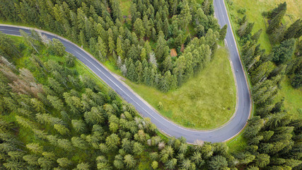 Wall Mural - Aerial view of twisting road among the forest and trees. Sunset field in Lithuania.