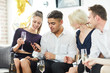 © pressmaster - Two girls and guy with champagne looking at smartphone of their friend to watch something curious at party