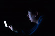 © twinsterphoto - Asian young man using phone in dark bedroom with blue light phone screen - unhealthy eyes strain concept.