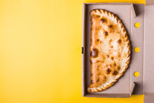Closed Pizza Calzone In Packing Box On Yellow Background