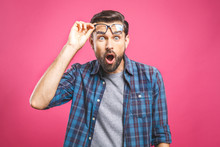 OMG! It's Incredible! Portrait Of Handsome Young Man In Glasses Looking At Camera While Standing Against Pink Background. Close Up Portrait Of Bearded Man Keeping His Mouth Open.