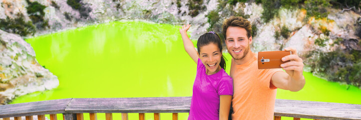 New Zealand tourism travel destination people lifestyle. Banner panorama. Couple tourists taking selfie travel destination, Waiotapu. Active geothermal green pond, Rotorua, north island, Wai-O-Tapu.