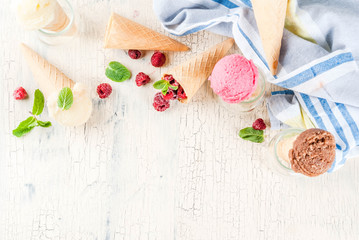  Summer sweet berries and desserts, various of ice cream flavor in cones pink (raspberry), vanilla and chocolate with mint on light concrete background copy space top view