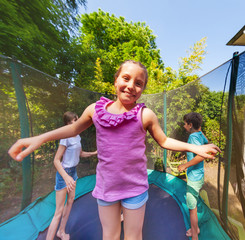 Wall Mural - Cute girl jumping on a trampoline with her friends