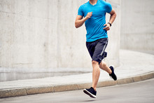 Athletic Man Jogging On Road In The City. Sport And Fitness Concept