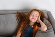 © Lisa Tichané - smiling redhead little girl resting on grey couch