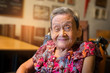 90 up of healthy woman,front view..Portrait of a happy elderly woman in colorful dress smiling while sitting in a restaurant. .