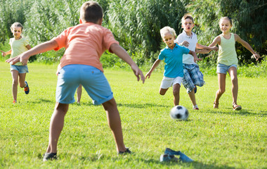 kids kicking football in park