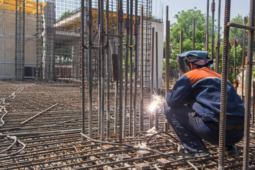 construction worker welding metal rebar for the pouring of foundation. candid, real people